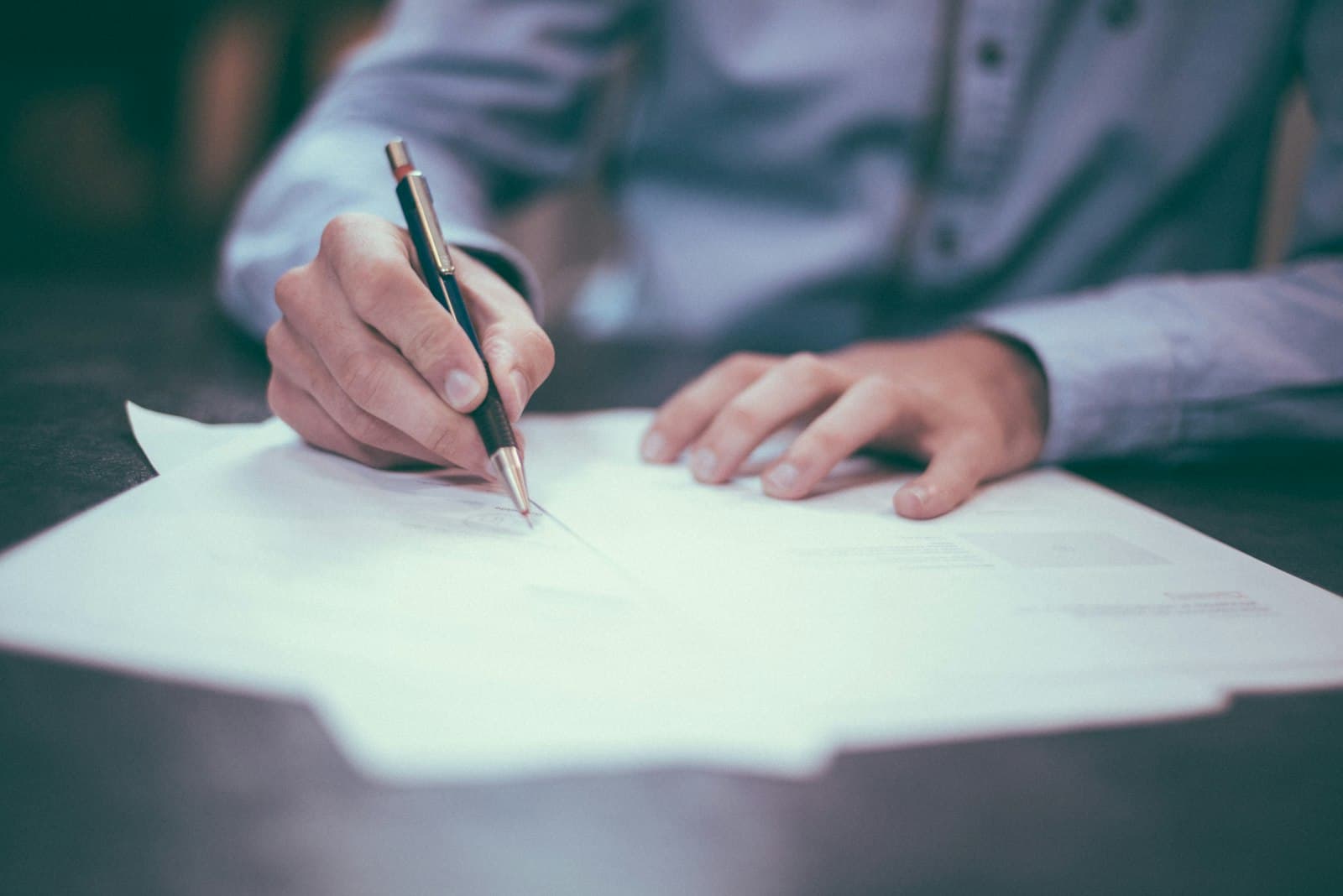 Hands completing paperwork with a fountain pen